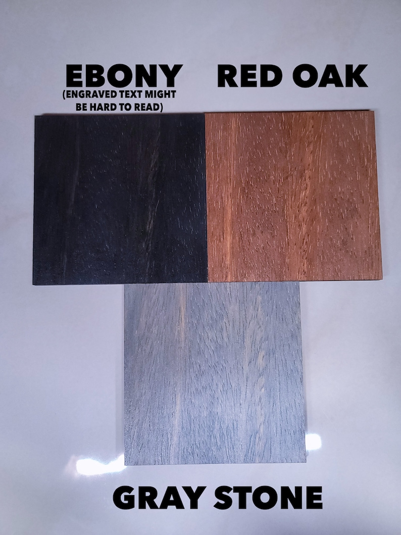 Puede incluir: Tres muestras de madera etiquetadas como "EBONY", "RED OAK" y "GRAY STONE". La muestra de &eacute;bano es negra, el roble rojo es marr&oacute;n y la piedra gris es gris claro. El texto "(ENGRAVED TEXT MIGHT BE HARD TO READ)" est&aacute; encima de la muestra de &eacute;bano.
