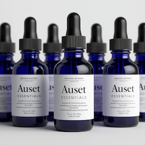 May include: A collection of dark blue glass bottles with black droppers. Each bottle has a white label with the text "Auset Essentials". The bottles are arranged in a group, suggesting a product line or set.