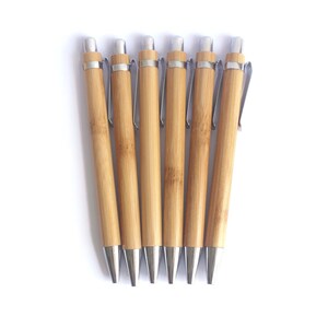 Op de afbeelding: Zes bamboe pennen met zilveren accenten en metalen clips. De pennen zijn in een rij gerangschikt, met de punten naar beneden gericht.