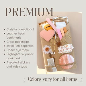 May include: A brown paper package containing a Christian devotional, a pink leather heart bookmark, gold cross paperclips, an initial pen paperclip, an under eye mask, highlighters, paper bookmarks, assorted stickers, and index tabs. The text reads PREMIUM.