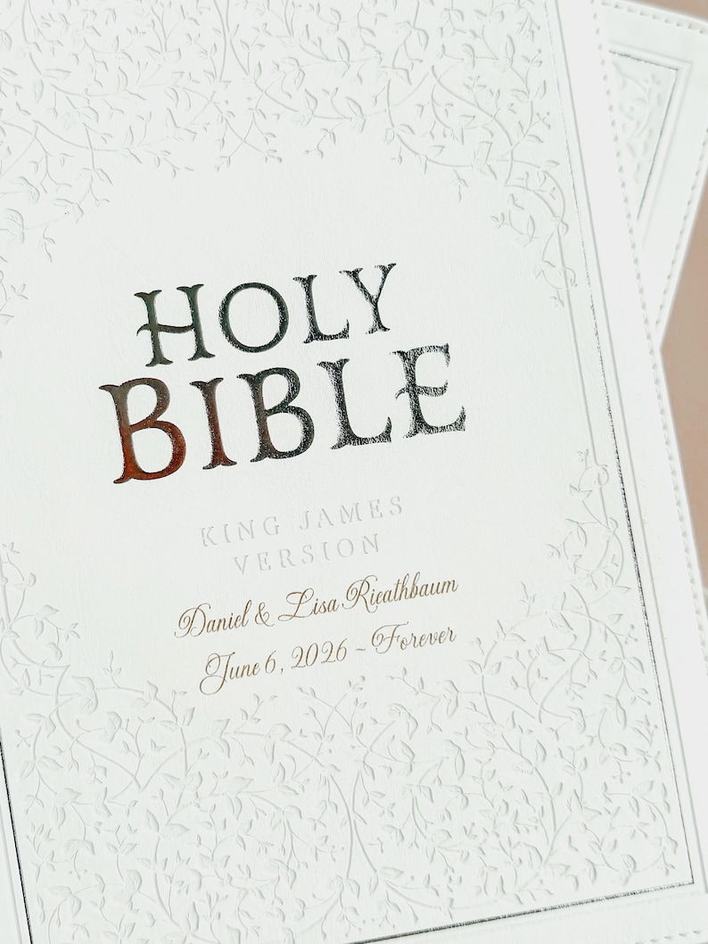 May include: A white Holy Bible with a textured vine pattern embossed on the cover. The text reads HOLY BIBLE, KING JAMES VERSION, Daniel & Lisa Rieathbaum, and June 6, 2026 - Forever in dark lettering centered on the front cover.
