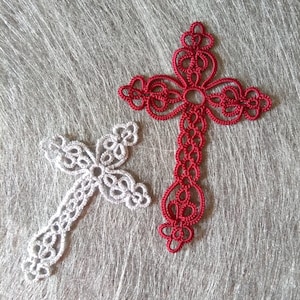 May include: Two crocheted crosses, one red and one white, on a gray textured background.