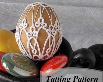 May include: A white crocheted egg cover with a delicate pattern. The cover is placed on top of a brown egg, which is surrounded by colorful glass stones. The image is labeled "Tatting Pattern".