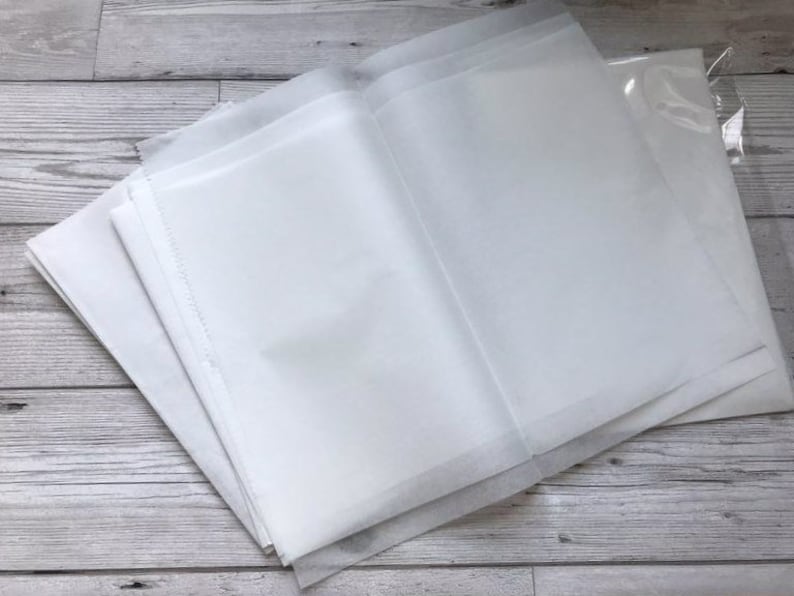 Pu&ograve; includere: Un mucchio di fogli di carta velina bianca, piegati a met&agrave;, con un foglio di plastica trasparente sopra.
