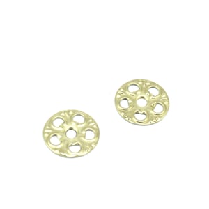 May include: Two gold-colored metal decorative round embellishments with a floral design. Each embellishment has a small hole in the center.