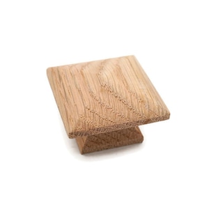 May include: A square wooden cabinet knob with a light brown finish.
