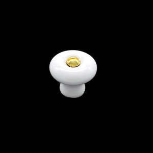 May include: White ceramic cabinet knob with a gold accent.