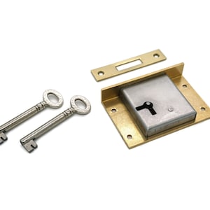 May include: A vintage-style lock set with two ornate keys, a brass faceplate, and a rectangular lock body. The lock and keys are silver-toned, and the faceplate is gold-toned. The set is designed for furniture or decorative use.