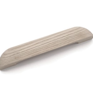 May include: A light brown wooden cabinet pull with a rounded rectangular shape. The pull has a smooth, slightly textured surface.