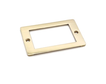 May include: A rectangular brass label holder with a recessed center and two screw holes. The label holder has a polished finish and is designed for use on drawers, cabinets, or other furniture. The hardware is a warm gold color.