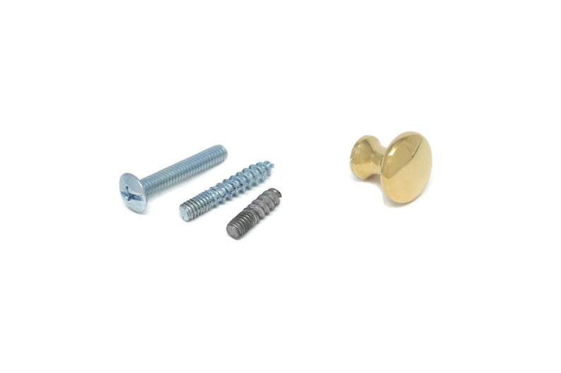 May include: An assortment of hardware components, including screws and a brass cabinet knob, are displayed against a white background. The screws vary in size and finish, while the knob has a polished, golden appearance. These items are suitable for furniture and home improvement projects.