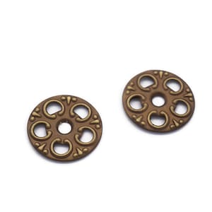 May include: Two gold-colored metal decorative buttons with a circular design and a central hole. The buttons have a raised, ornate pattern around the edge.