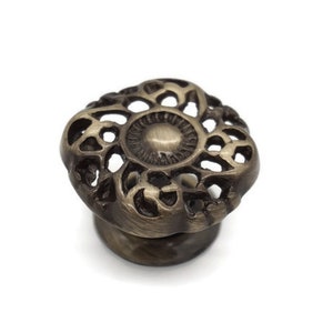 May include: A decorative brass cabinet knob with a detailed floral design.