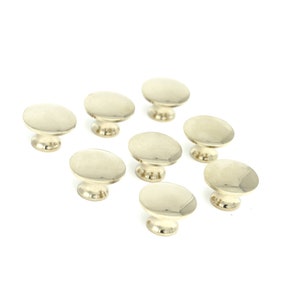 May include: A set of ten gold-toned cabinet knobs with a round, slightly domed top and a short, cylindrical base.