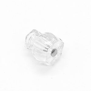 May include: A clear glass cabinet knob with a silver metal screw. The knob has a faceted design.