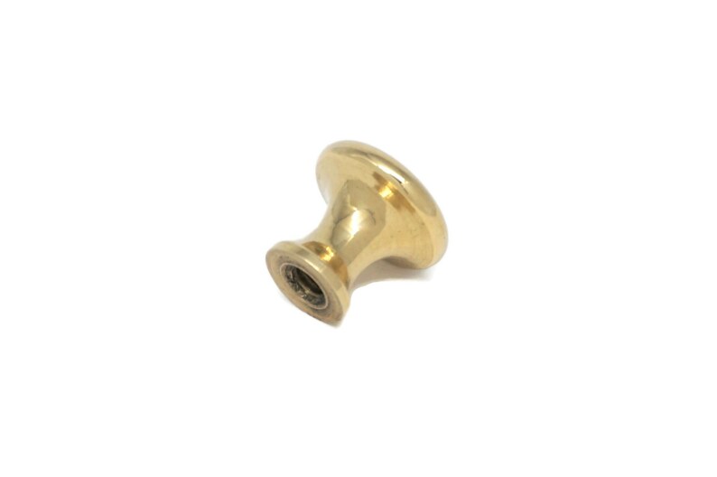May include: A single, gold-colored cabinet knob with a rounded top and a cylindrical base. The knob is made of a shiny, metallic material and is set against a white background. This hardware is suitable for drawers and cabinets.
