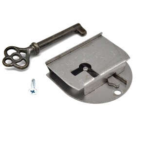 May include: A silver-toned keyhole lock with a key and a screw. The key is ornate with a decorative, flower-shaped head.
