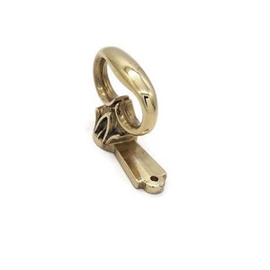 May include: A gold-toned metal hook with a decorative design. The hook is designed to be mounted on a wall.