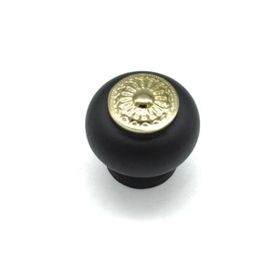May include: Black round cabinet knob with a gold decorative center.