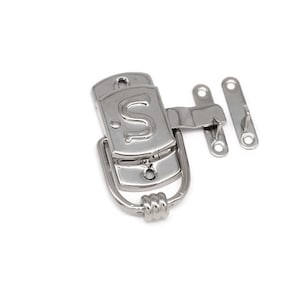 May include: Silver-toned metal latch with a decorative ring handle and a small plate with the letter "S" engraved on it. The latch has two metal plates with holes for mounting.