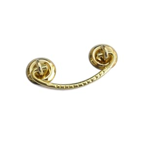 May include: Gold-toned metal drawer pull with a curved design and two round knobs.
