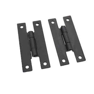 May include: Two black metal hinges with a matte finish. The hinges are closed and have a simple design.