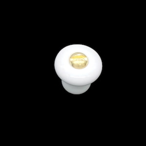 May include: White ceramic knob with a gold center. The knob is round and has a small stem.