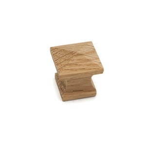May include: A square wooden cabinet knob with a light brown finish.