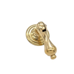 May include: A gold-toned cabinet pull with a round base and a curved handle.