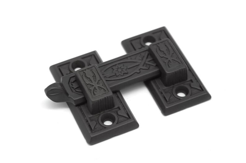 May include: Black metal door latch with an ornate design. The latch has a lever that can be moved to lock or unlock the door.