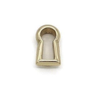 May include: A gold keyhole charm with a rounded top and a rectangular base.