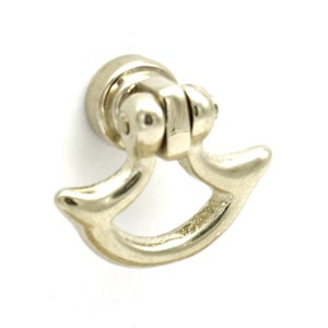 May include: A silver-toned metal cabinet pull with a curved, crescent-shaped design. The pull has a hinged, swiveling base.