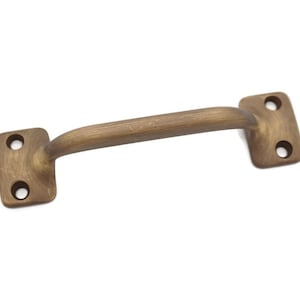 May include: A brushed brass cabinet pull with a curved handle and square ends. The pull has two holes for mounting.