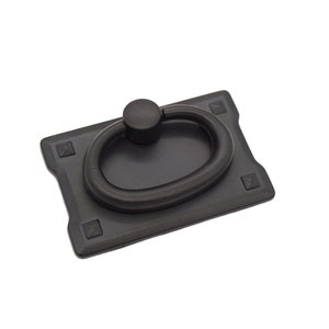 May include: Black metal cabinet pull with a ring handle. The pull has a rectangular base with rounded corners and four small square accents.