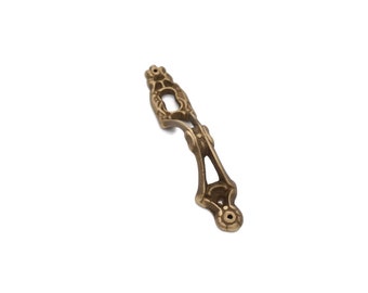 May include: Ornate, antique-style bronze drawer pull with a decorative openwork design. The pull features a central oval opening and two mounting holes at the base. Ideal for furniture restoration or adding vintage charm.