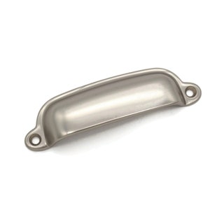 May include: A silver cabinet pull with a curved, rectangular shape and rounded edges. The pull has two small holes for mounting.