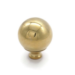 May include: A polished gold round cabinet knob with a smooth, spherical design.