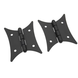 May include: Two black butterfly hinges with a decorative design. The hinges are made of metal and have a matte finish.