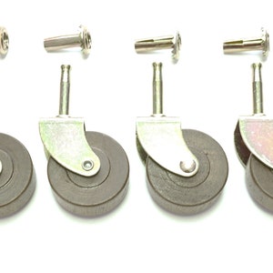 May include: Four dark gray furniture casters with metal brackets and stems, along with four metal sockets. The casters have a round wheel design and are set against a white background.