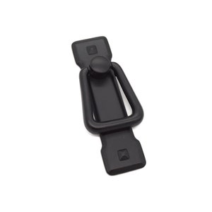 May include: Black metal cabinet pull with a rectangular shape and a ring handle. The pull has a matte finish.
