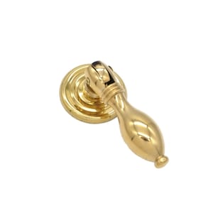 May include: A gold-toned cabinet pull with a round base and a long, curved handle.