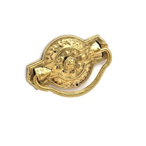 May include: Gold-toned metal cabinet pull with a floral design and a decorative ring pull.