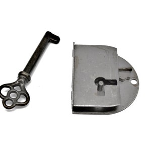 May include: A silver keyhole cover with a keyhole and a small metal pin. A silver key with a decorative, ornate head is also shown.