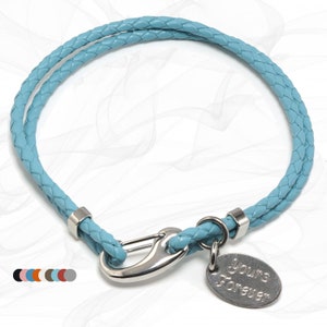 Könnte beinhalten: Ein hellblaues geflochtenes Lederarmband mit einem silbernen Verschluss und einem silbernen Anhänger mit der Aufschrift "yours forever".