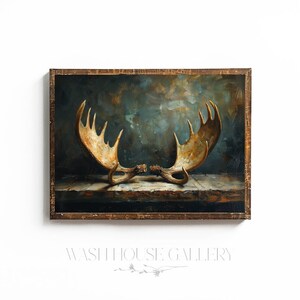 May include: A framed painting of a pair of moose antlers against a dark blue and green background. The antlers are a light brown color and are positioned in a way that suggests they are fighting.