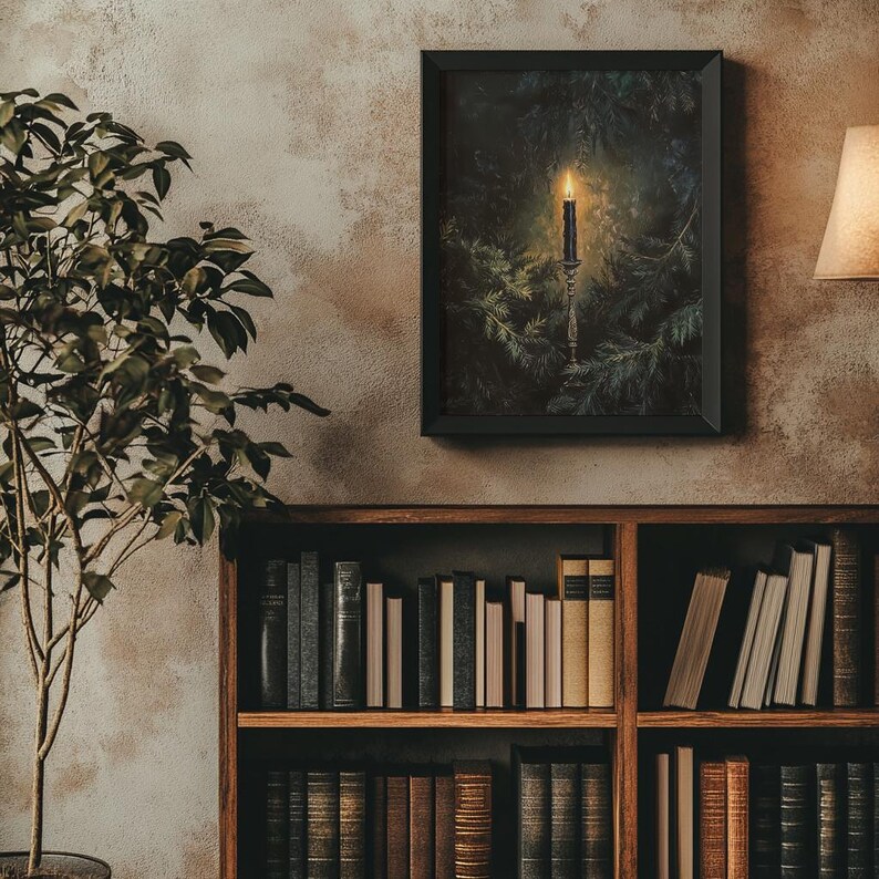 May include: A framed print of a candle burning in a dark forest setting. The candle is on a candlestick and surrounded by pine branches. The image has a dark, moody feel.