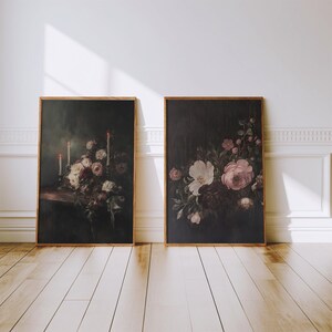 Puede incluir: Dos pinturas enmarcadas con fondos oscuros. La pintura de la izquierda presenta una naturaleza muerta de flores blancas y rosas con tres velas encendidas. La pintura de la derecha presenta un ramo de flores rosas y blancas.