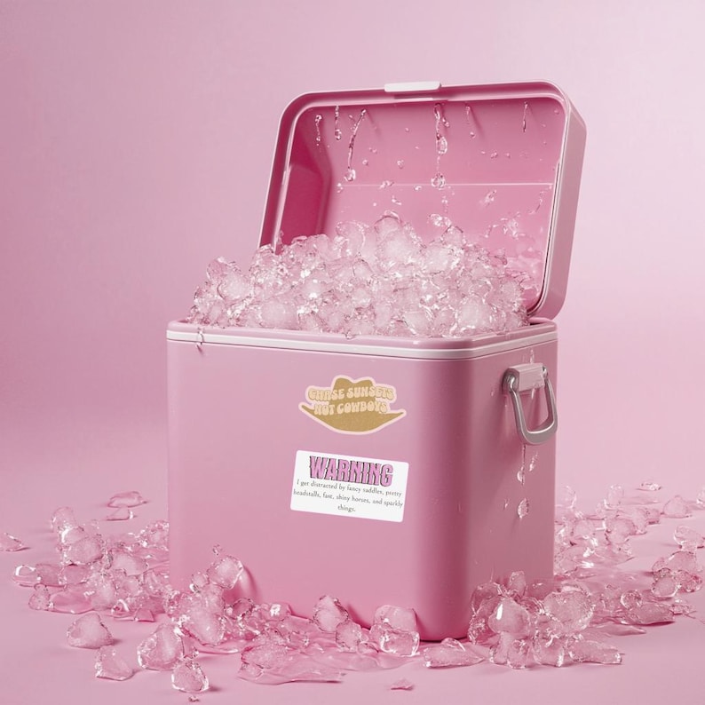 May include: A pink cooler filled with ice cubes. The cooler features two stickers: a tan cowboy hat shape with the text "CHASE SUNSETS NOT COWBOYS" and a rectangular white sticker with the text "WARNING I get distracted by fancy saddles, pretty headstalls, fun, shiny horses, and sparkly things."