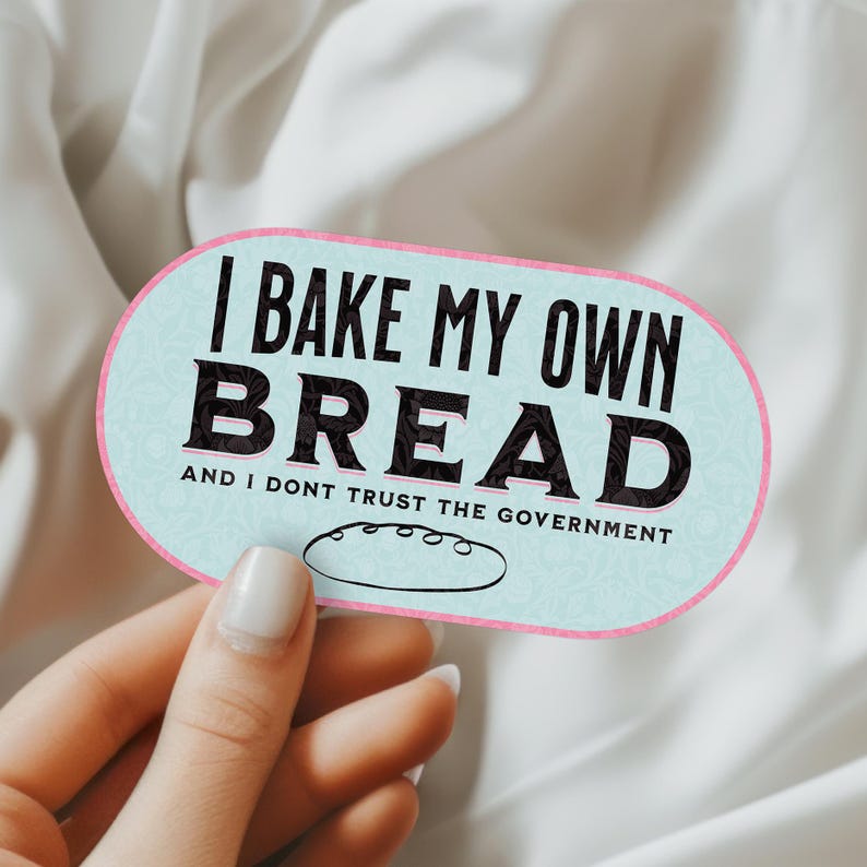 May include: A light blue and pink oval sticker with the text "I bake my own bread and I don't trust the government". A small illustration of a loaf of bread is below the text.