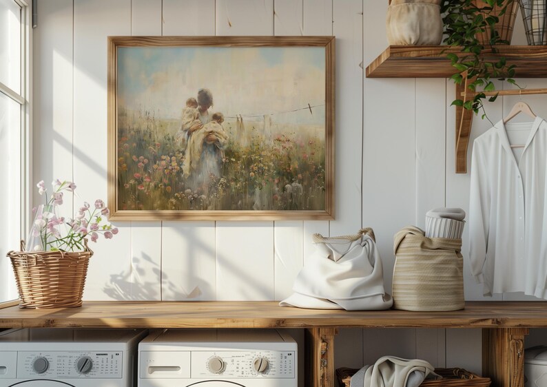 May include: A framed painting of a woman holding two children in a field of flowers. The painting is in a light wood frame and hangs on a white wall.